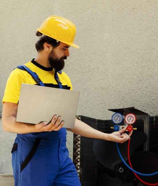 Smiling competent mechanic calibrating pressure measurement device during comissioned air conditioner troubleshooting. Adept repairman reading vacuum pressure of condenser liquids and gases